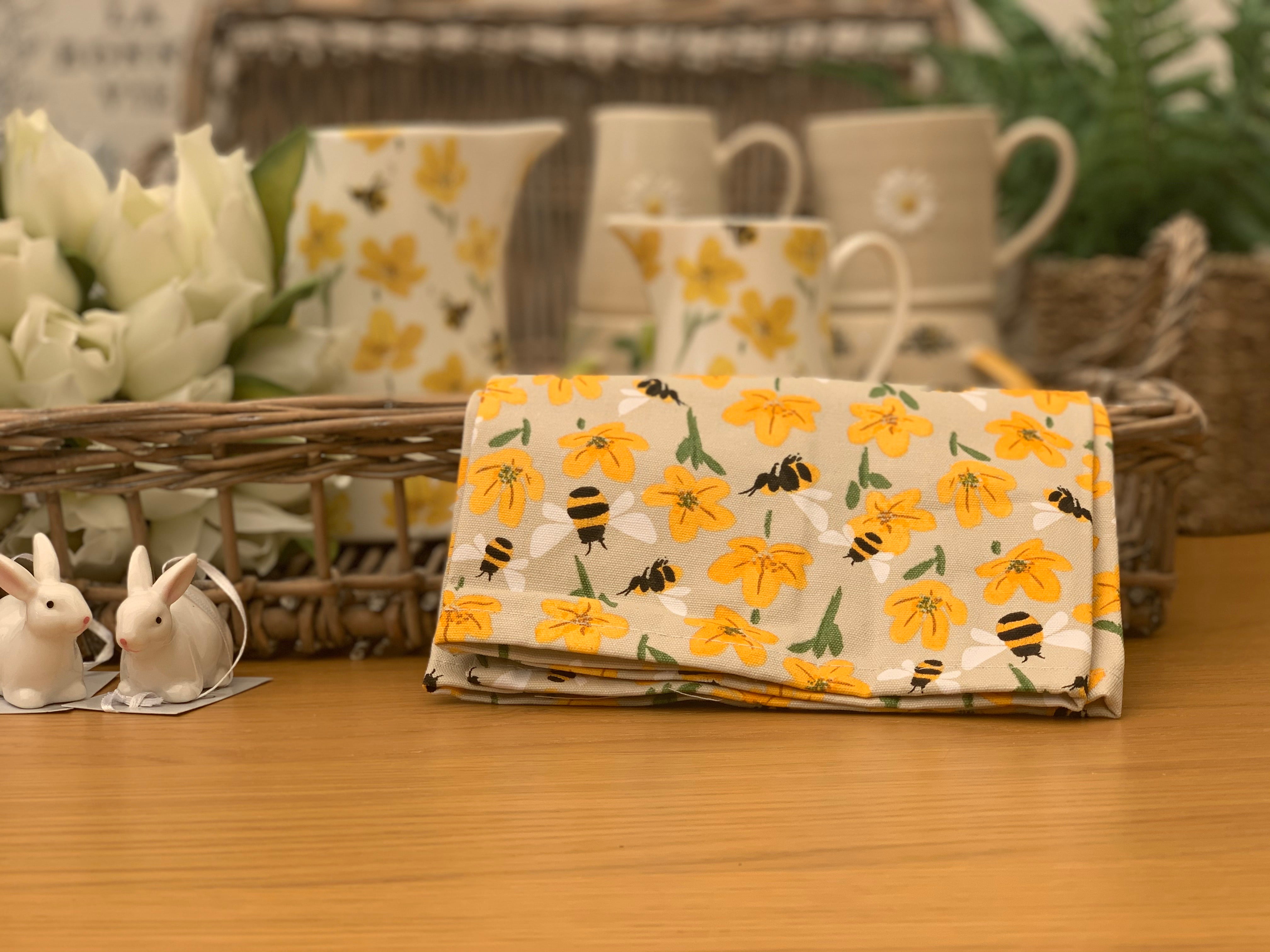 Bees and buttercups tea towel from Sable Homeware featuring floral and insect patterns, displayed on a kitchen surface.