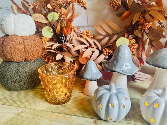 Dark peach glass tealight holder by Sable Homeware, featuring a candle inside, set against an autumn scene background.