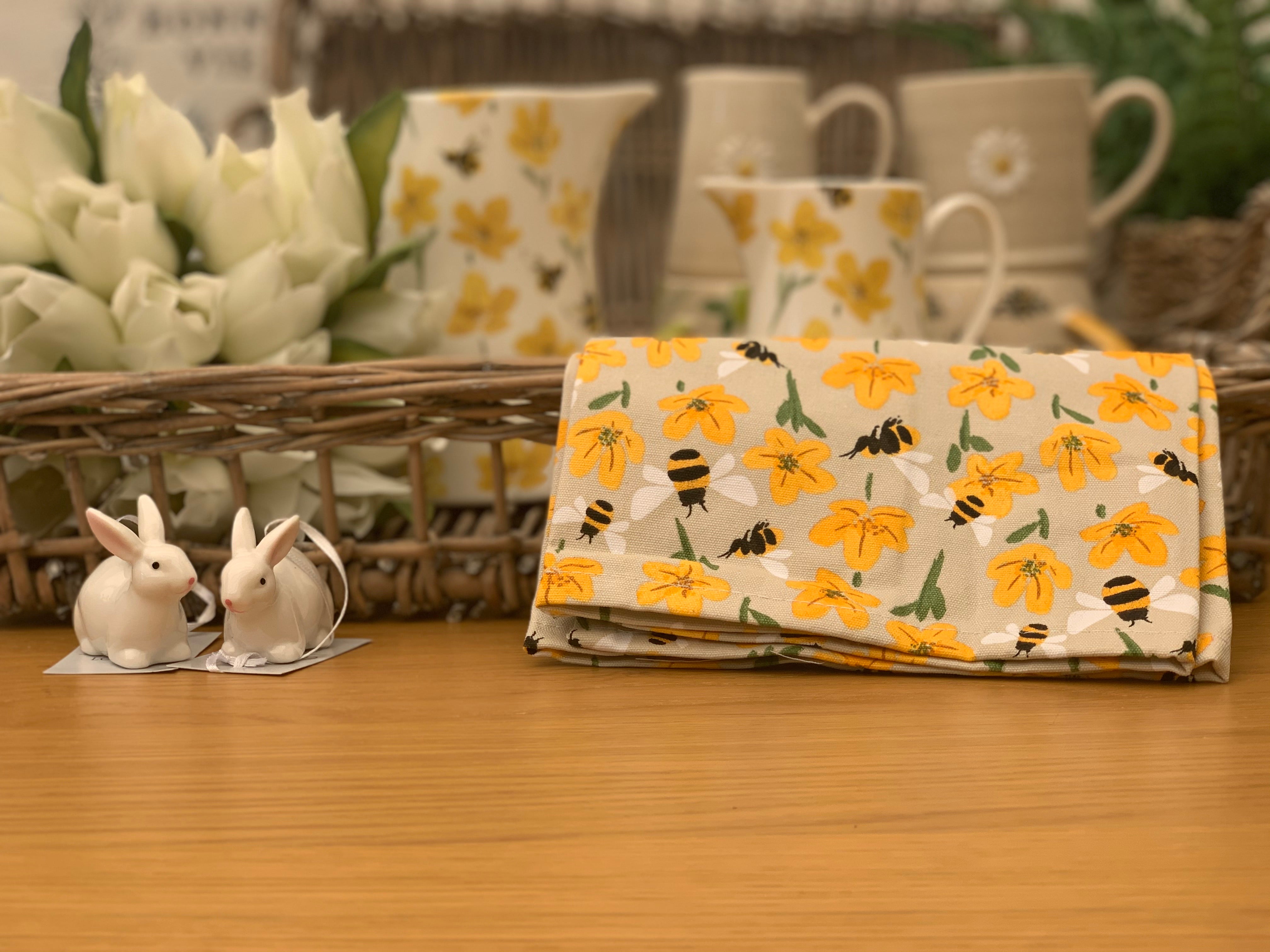 Bees and buttercups tea towel from Sable Homeware, featuring a floral and insect design, displayed on a kitchen counter.